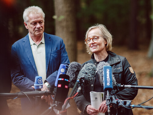 Bundesminister Alois Rainer und Dr. Nicole Wellbrock bei der Vorstellung des Waldzustandsberichts. Zwei Personen stehen im Wald vor Mikrofonen.