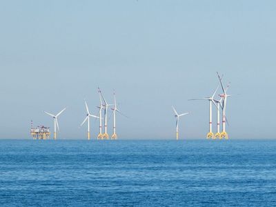 Mehrere Windkrafträder auf offener See mit einer Versorgungstation
