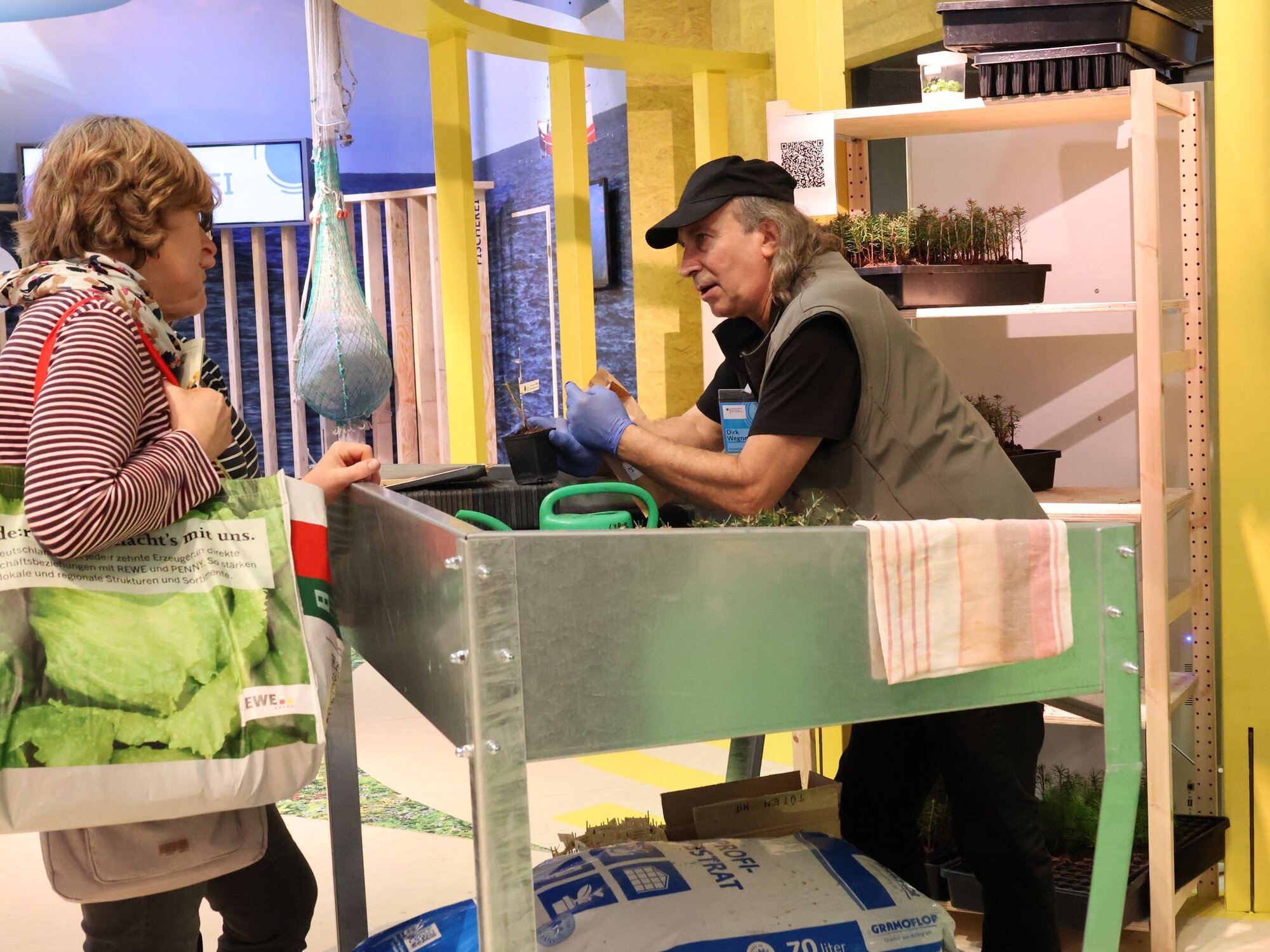 Am Stand des Instituts für Forstgenetik werden junge Douglasien verteilt. Zwei Personen an einem Messestand