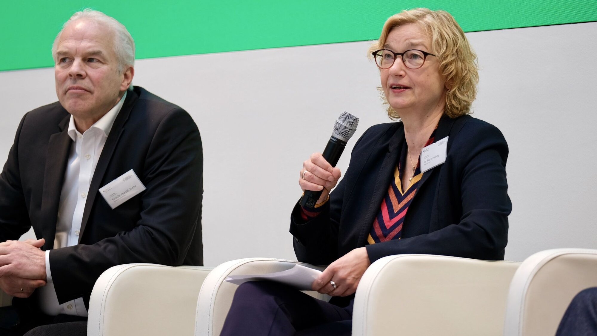 Prof. Dr. Hiltrud Nieberg und Prof. Dr. Harald Grethe bei einer Diskussionsrunde auf der Bühne. Zwei Personen sitzen mit Mikrofon auf Sesseln auf einer Bühne.