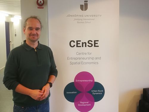 Jan Cornelius Peters as a guest at the Centre for Entrepreneurship and Spatial Economics (CEnSE), standing next to a display for the event.