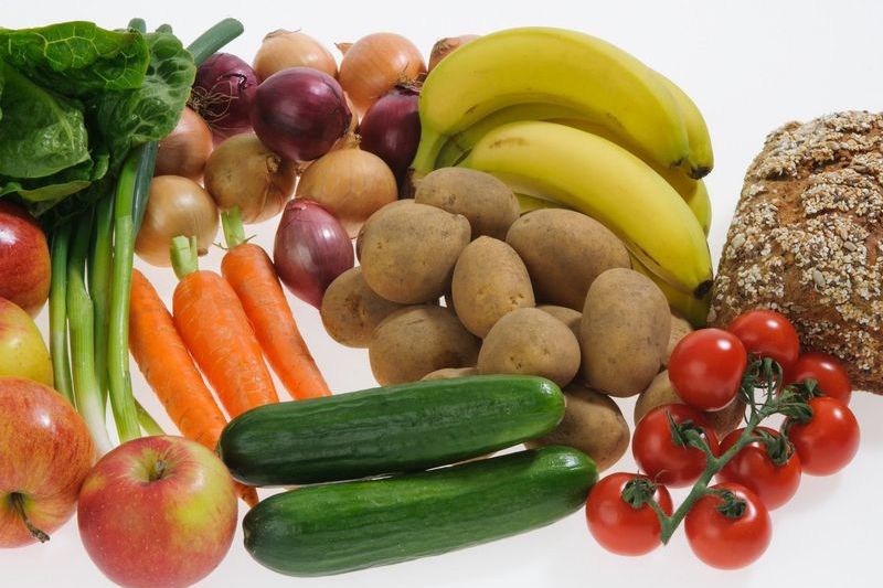 Bananas, apples, tomatoes, green onions, potatoes, lettuce, onions, cucumber, carrots and wholemeal bread in one picture