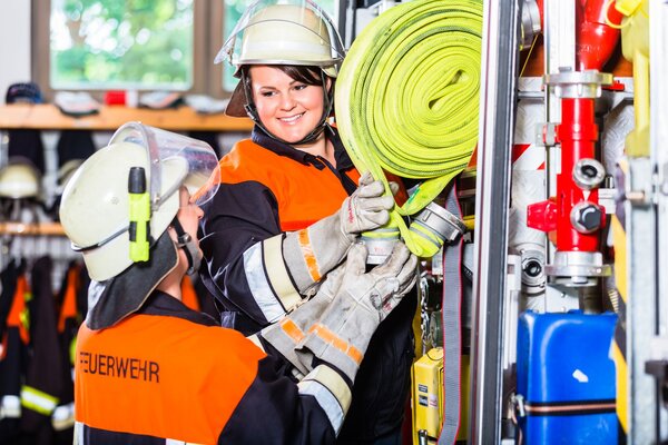 Freiwillige Feuerwehr, nicht nur Männersache. Feuerwehrfrauen verladen Schläuche in das Einsatzfahrzeug.