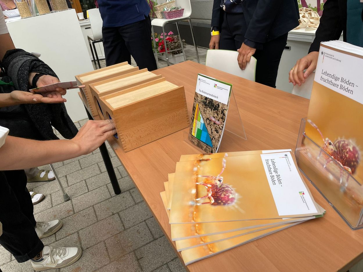 Fühlboxen, die mit drei verschiedenen Böden befüllt sind, an einem Informationsstand beim Tag der offenen Tür der Bundesanstalt für Landwirtschaft und Ernährung