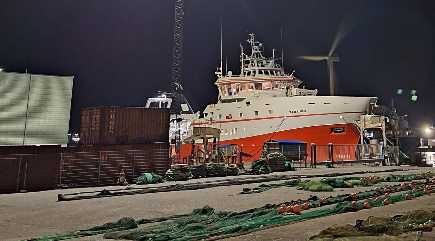 Die Tarajoq im nächtlichen Hafen. Im Vordergrund liegen Netze ausgebreitet auf dem Boden.