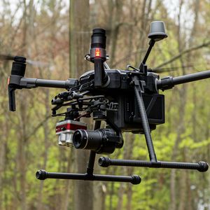 Drohne im Flug vor Baumbestand.