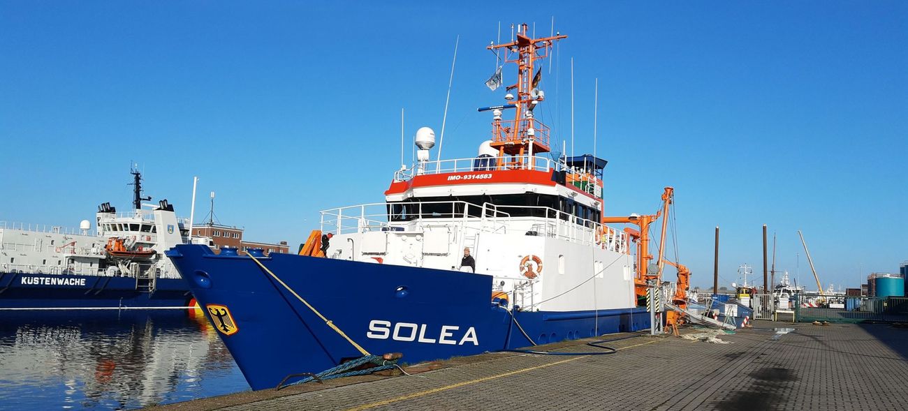 Ein Schiff mit blauem Rumpf und weißen und orangenen Aufbauten.