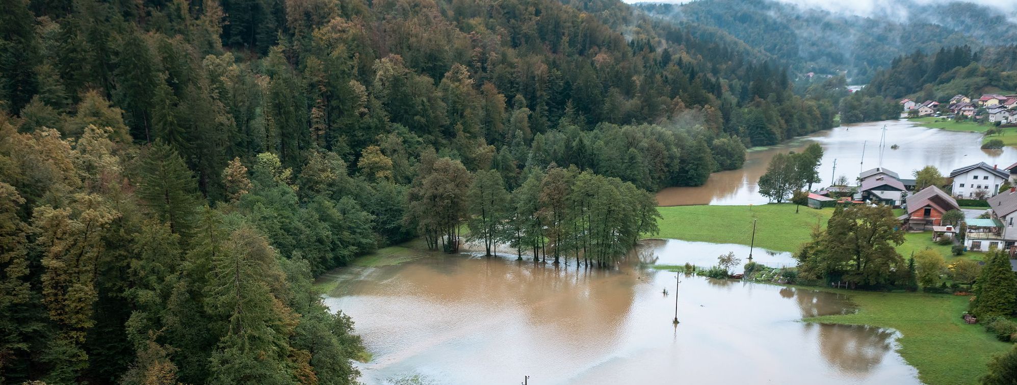 Ein Feld, ein Wald und ein Dorf stehen teilweise unter Wasser