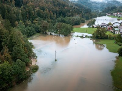 Ein Feld, ein Wald und ein Dorf stehen teilweise unter Wasser