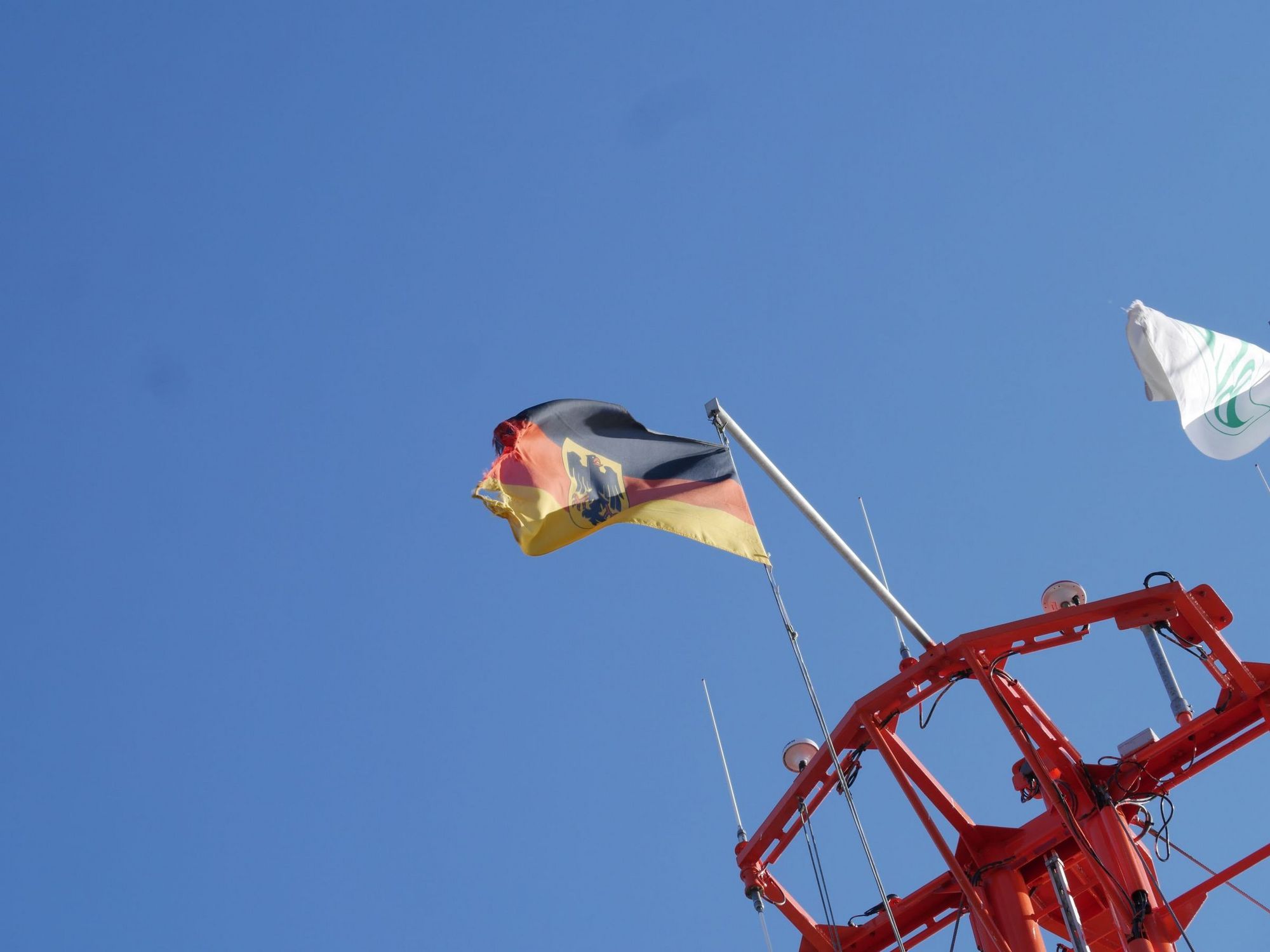 Die Deutschlandfahne weht vor blauem Himmel im Wind