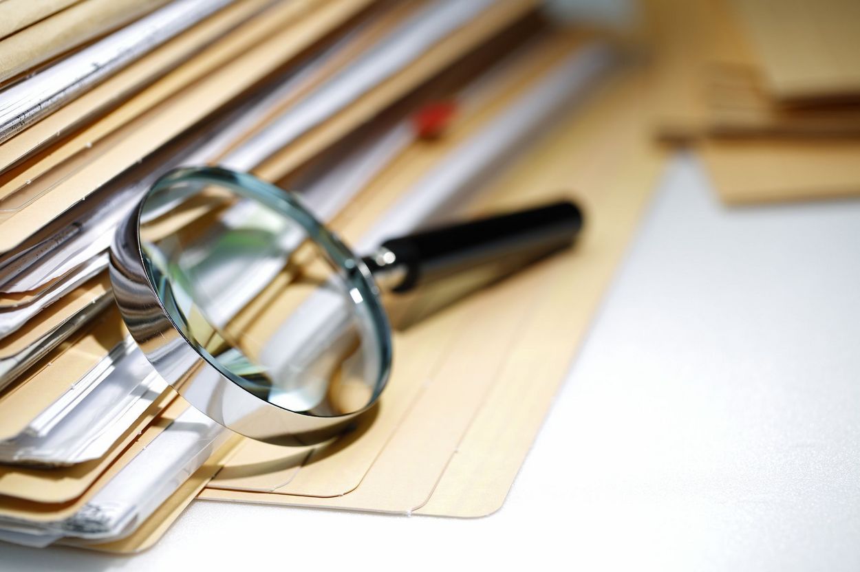 A magnifying glass leans against a pile of documents.