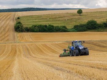 A tractor drives across a grain field with an attached machine.