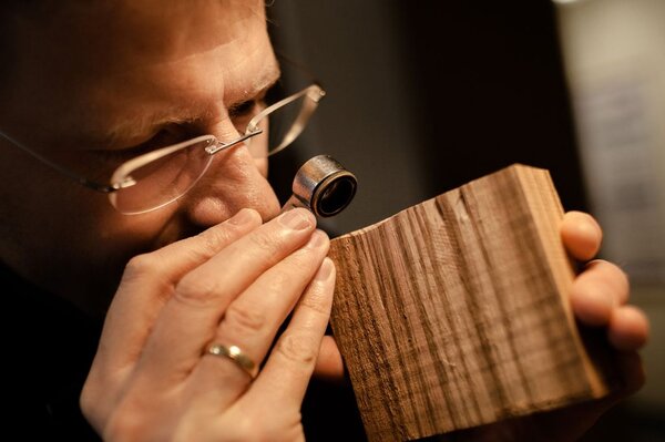 Ein Wissenschaftler schaut durch eine Lupe auf ein Stück Holz