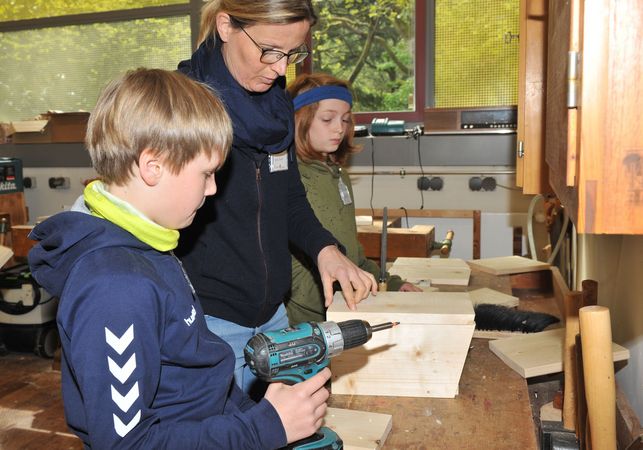 drei Personen arbeiten mit Holz