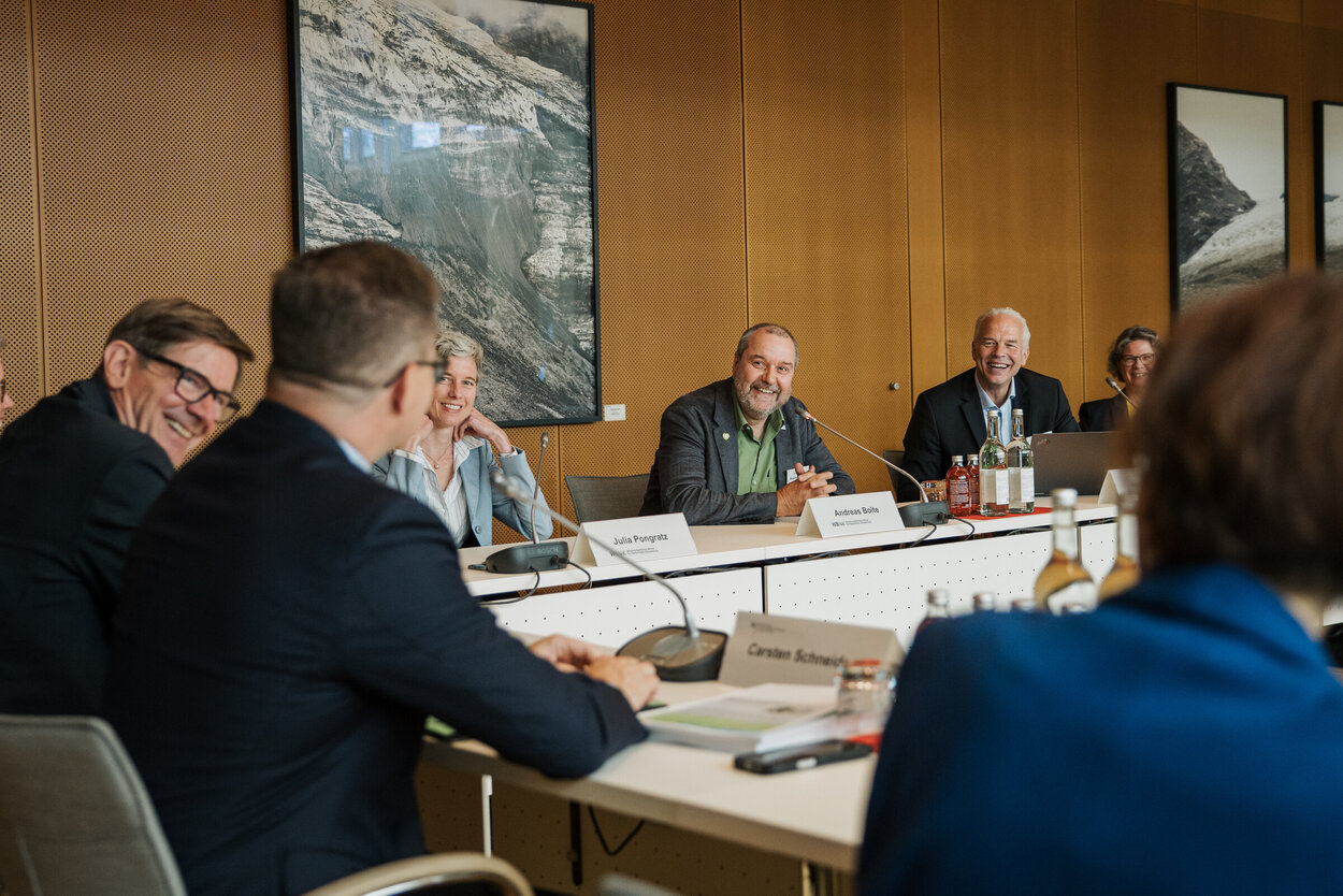 Übergabe des Berichts des Wissenschaftlichen Beirats für Natürlichen Klimaschutz an Bundesminister Carsten Schneider. Mehrere Personen sitzen um einen Tisch in U-Form.
