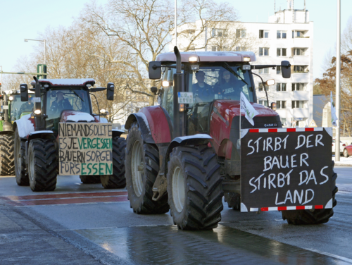 In vielen deutschen Städten sorgten die Treckerdemos für stundenlange Staus. Traktoren mit Protestschildern von Landwirten fahren durch eine Straße.