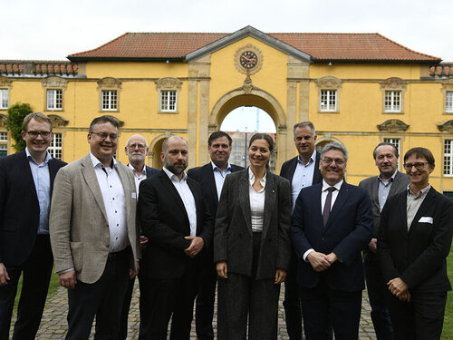 Die Beteiligten am KI-Reallabor Agrar bei der feierlichen Eröffnung. Zehn Personen stehen vor einem gelben Gebäude.