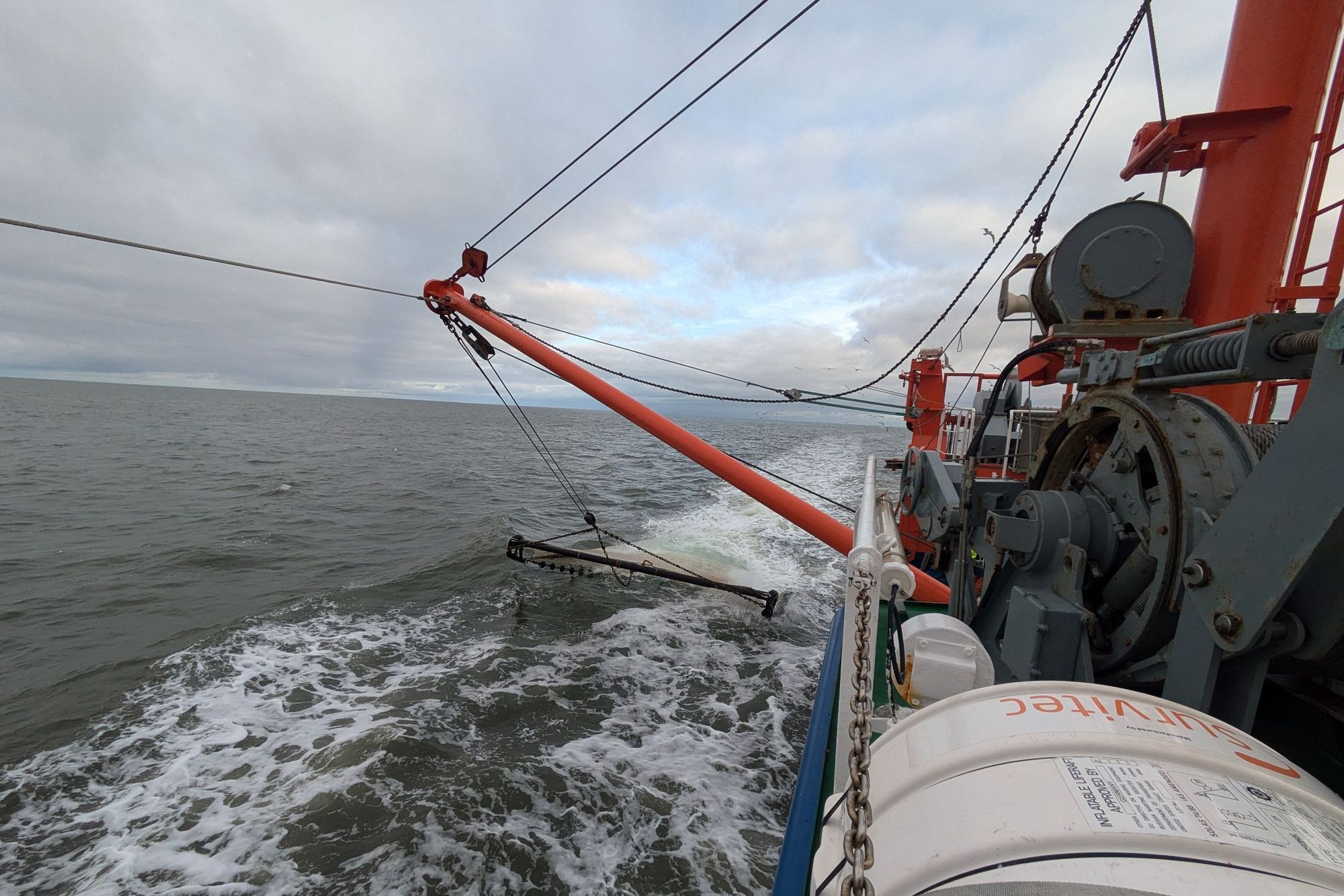 Die Baumkurre hängt auf der linken Schiffsseite im Wasser, Blick nach hinten.