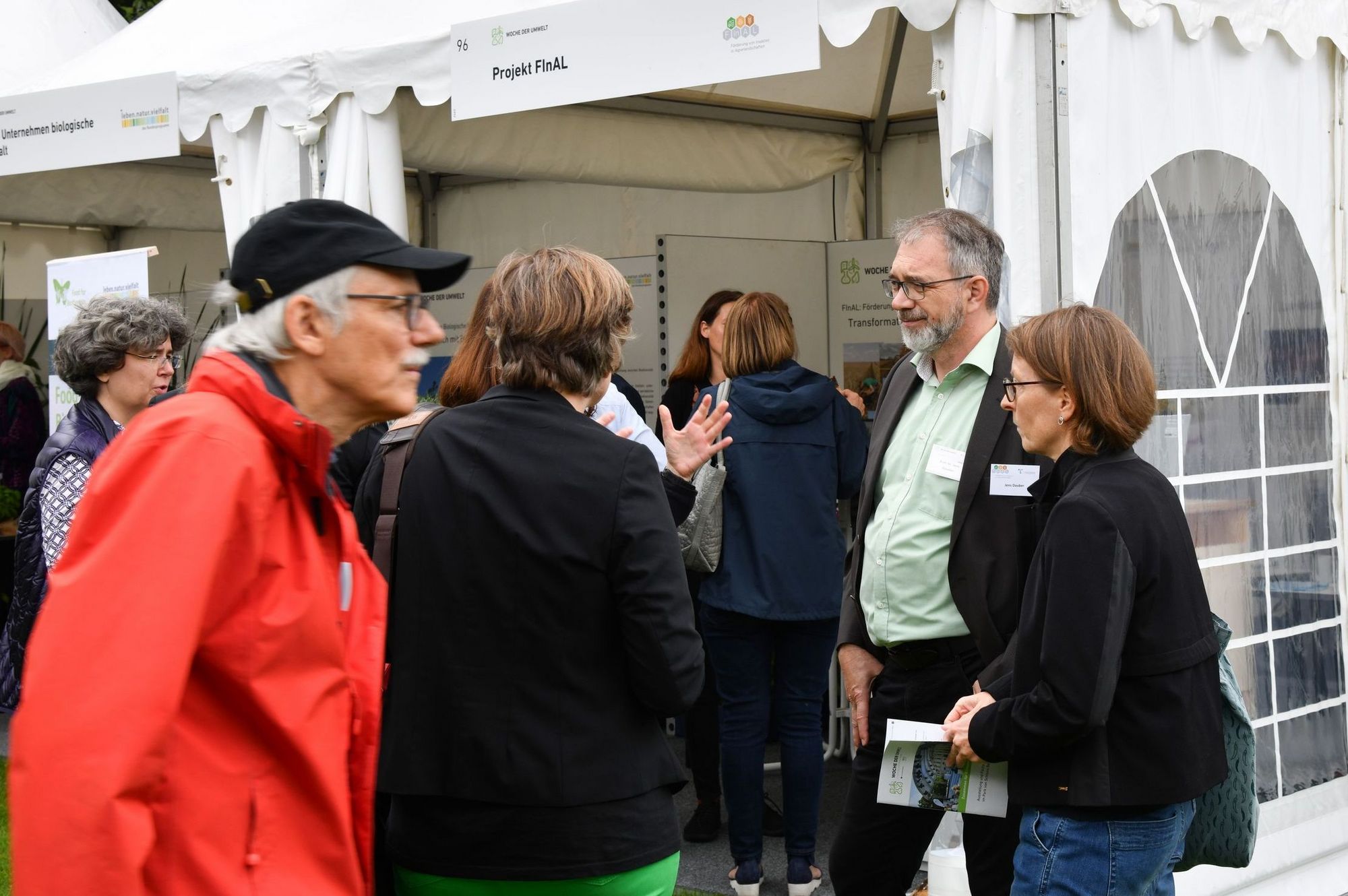 Mehrere Personen stehen vor einem Pavillon mit Informationen zum FinAl Projekt