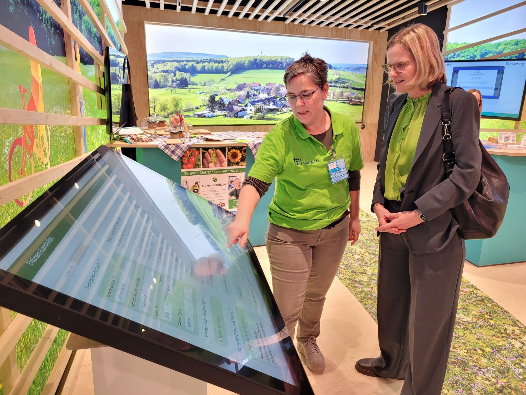 Birgit Kleinschmit, die designierte Präsidentin des Thünen-Instituts, und Johanna Fick vom Thünen-Institut für Lebensverhältnisse in ländlichen Räumen am großen Touchscreen mit dem Thünen-Landatlas. Zwei Personen stehen vor einem großen Bildschirm.