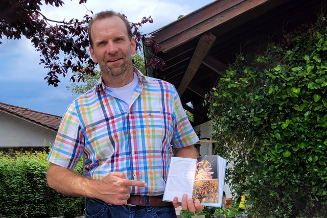 Thomas Guggemoos der Fotograf der Tonerdhummel-Königin Portraiit des Fotografen mit einem Bestimmungsbuch in der Hand