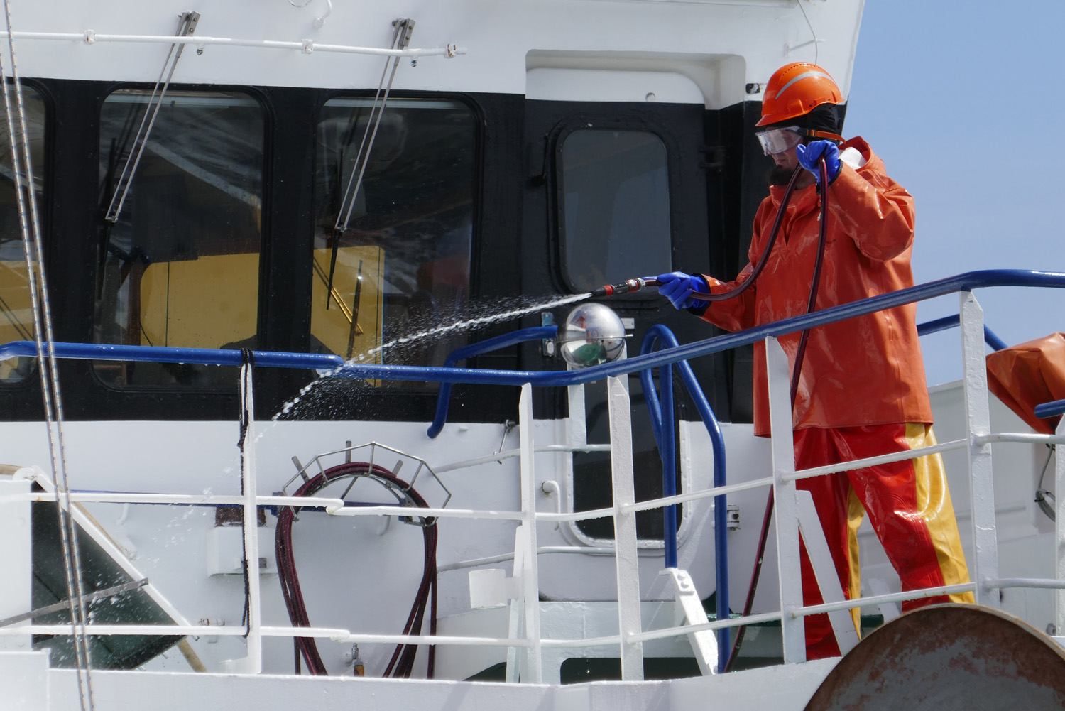 Nach der Reise ist vor der Reise: Die Matrosen haben für die nächste Tour schon Klar Schiff gemacht. Ein Seemann reinigt vor der Brücke das Deck mit einem Schlauch.