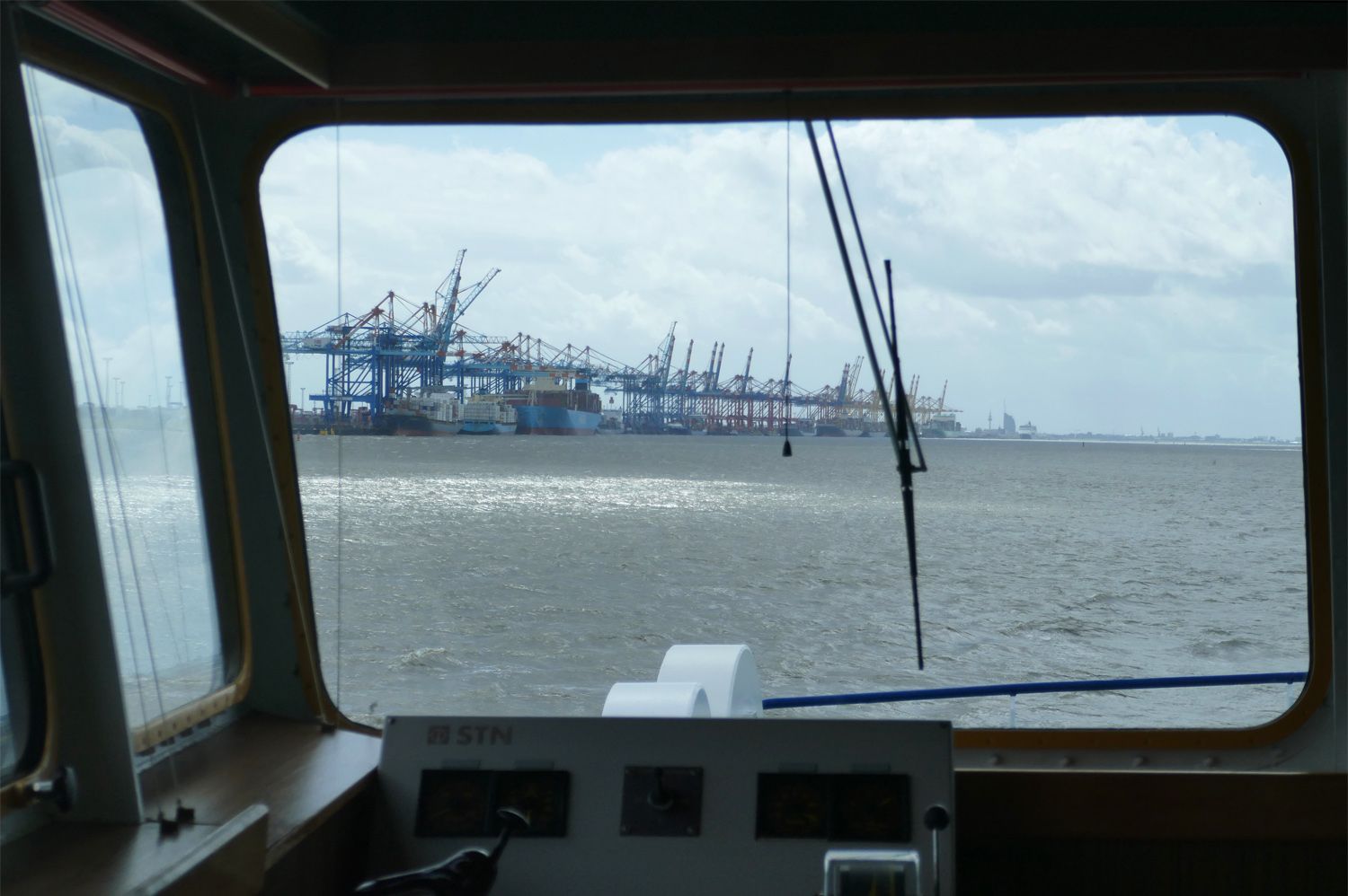 Rolling Home: Wir fahren wieder auf der Weser. Blick von der Brücke über die Weser auf die Hafenanlage mit Ladekränen.